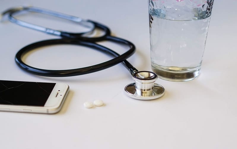 Closeup of a stethoscope, aspirin, glass of water and a mobile phone