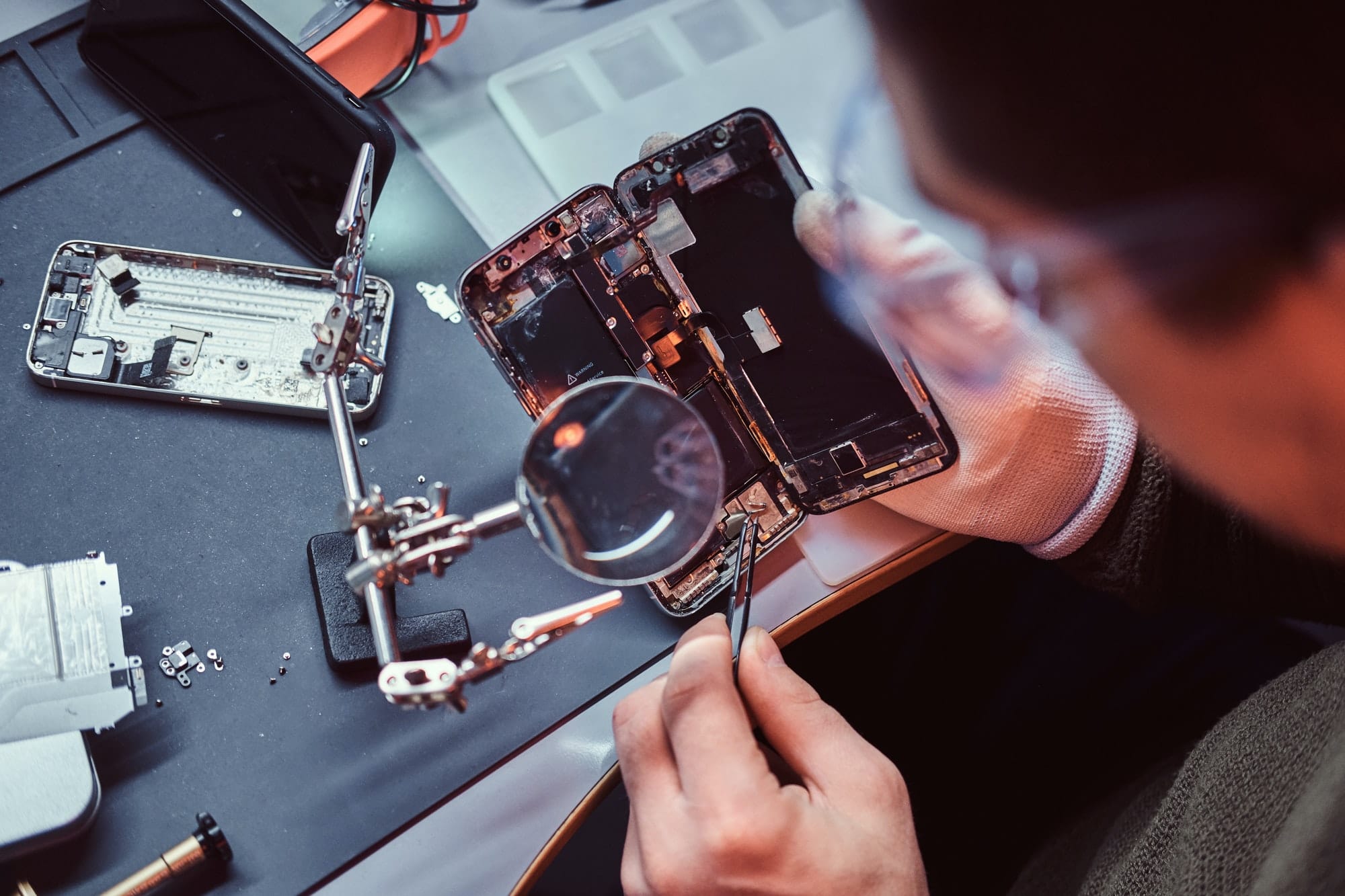 Technician carefully inspect the internal parts of the smartphone in a modern repair shop